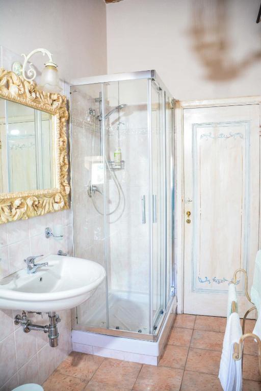 Dettaglio del bagno con box doccia, lavabo e specchio con cornice dorata.